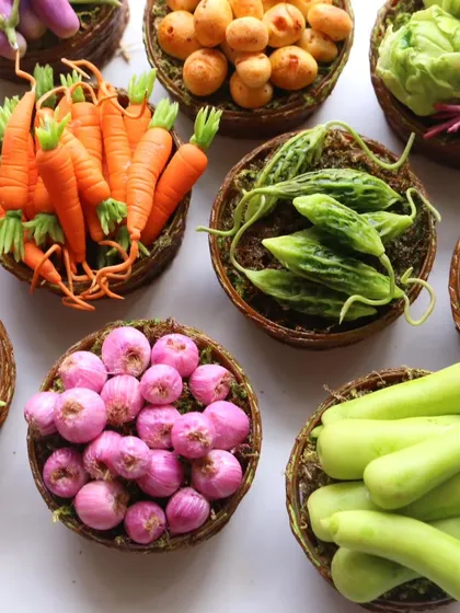 A beautiful flat lay of various vegetable baskets, including carrots, bitter gourd, onions, and bottle gourd.