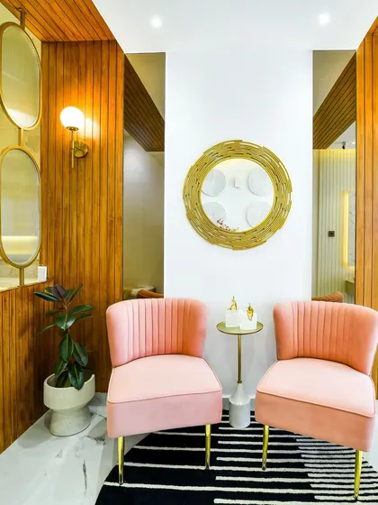 Another angle of the elegant entryway, showing the beautiful interplay of the wood paneling, the round gold mirror, and the soft pink chairs. The design feels layered, warm, and incredibly chic.