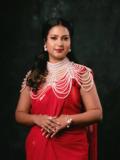 A regal portrait in a red saree, adorned with a statement pearl necklace. The dark, moody background makes the red and the pearls stand out, creating a look of pure elegance.