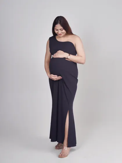 A full-body studio shot of a mother-to-be in a sleek, one-shoulder black maternity gown. This minimalist style is perfect for creating modern and sophisticated pregnancy portraits.