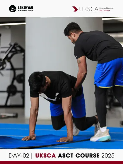A coach demonstrates proper form for a bear crawl, a fundamental movement pattern covered on Day 2 that improves core stability and coordination.