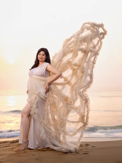The flowing gown mimics the shape of wings, creating a powerful and angelic image of the mom-to-be against the morning sky.