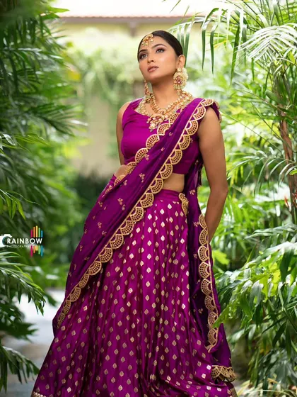 A stunning purple brocade half saree, perfect for traditional South Indian functions. The rich fabric and gold border create a timeless and regal look.