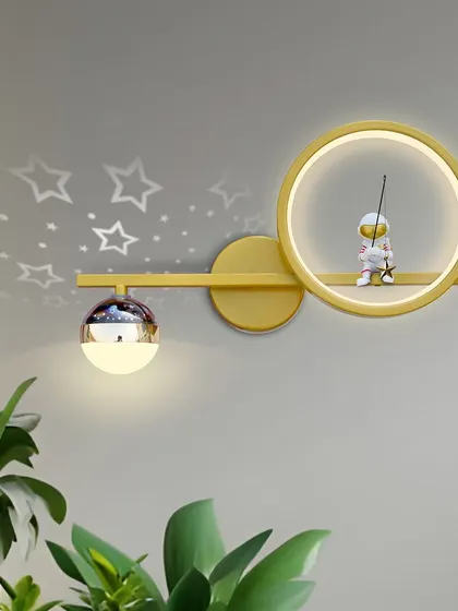 This unique wall light features a little astronaut fishing for stars. The light projects a starry pattern on the wall, creating a magical effect for any child's room.