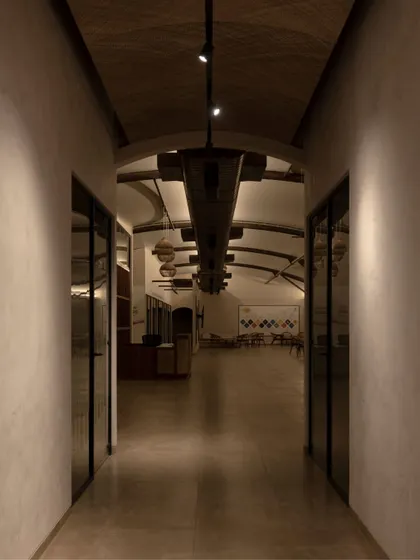 A long, vaulted corridor with dramatic lighting leads into the main office area, setting a modern and sophisticated tone.