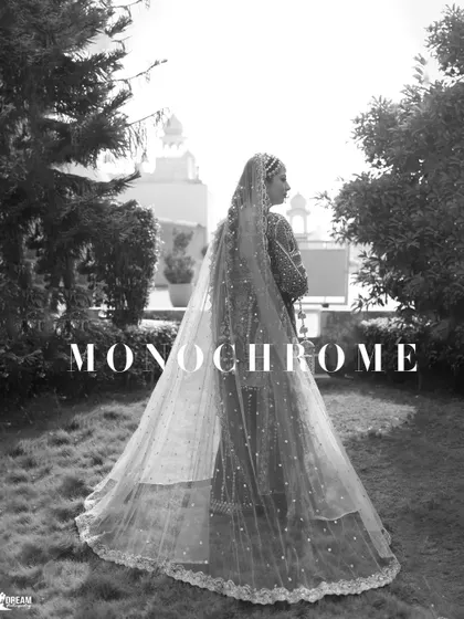 A stunning black and white photo of bride Mannat, capturing the beautiful silhouette of her and her long, flowing veil against the light.