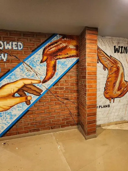A wider view showing the "Hallowed Be Thy Wing" and "Wing It On!" murals side-by-side.