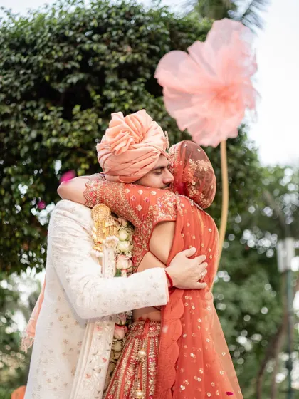 A heartfelt hug between the newly married couple, surrounded by lush greenery and beautiful floral decor.