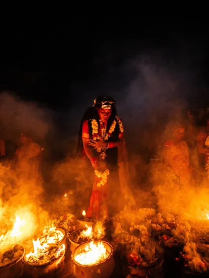 Surrounded by fire and smoke, a devotee at Kulasai embodies a deity. The image is atmospheric, capturing the raw and primal energy of the festival.