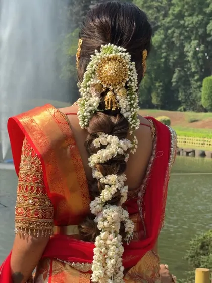 A detailed view of the traditional South Indian bridal hairstyle, adorned with flowers and gold accessories, which complements the saree drape perfectly.