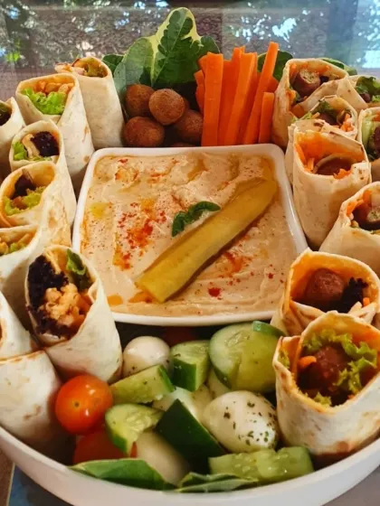Mini falafel and Sharwarma rolls circle a dip on our platter, with vegetables and little bites arranged for an afternoon snack.