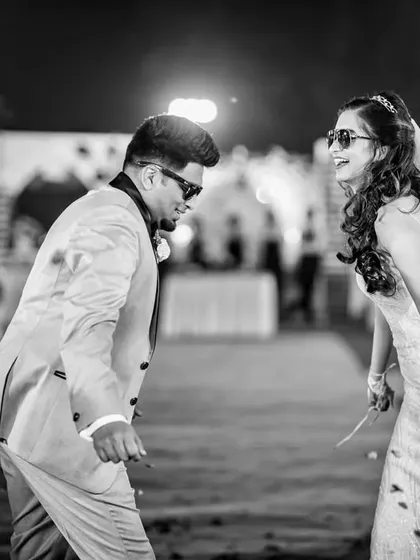 The couple facing each other and dancing during their entrance. This black and white photo captures a candid moment of shared fun.