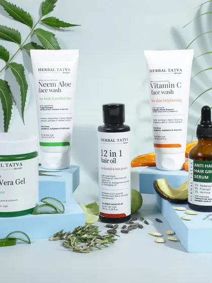 A comprehensive group shot of a herbal skincare line. The products are arranged on blue podiums with their respective natural ingredients, creating a clean, informative, and visually appealing display.