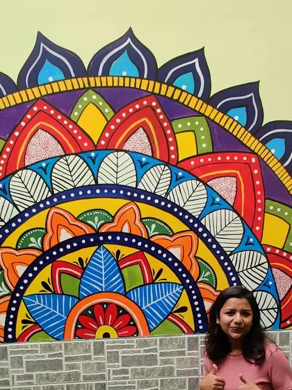 Another shot of me with the finished mandala wall art. The bright, contrasting colors make the design pop against the light yellow wall.