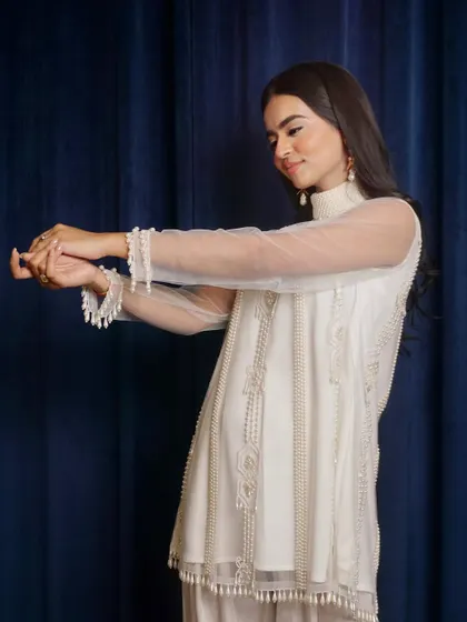 A shot focusing on the delicate pearl detailing on the cuffs of the sheer sleeves. Detail shots like this are essential for showing product quality.