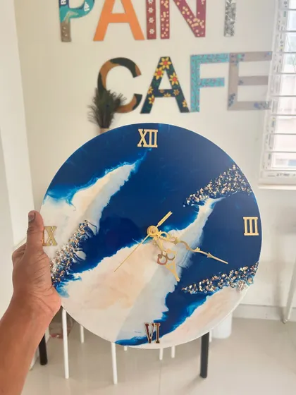 A beautiful resin clock with abstract blue and white waves, accented with gold flakes. Each piece is a unique expression of the creator's style.