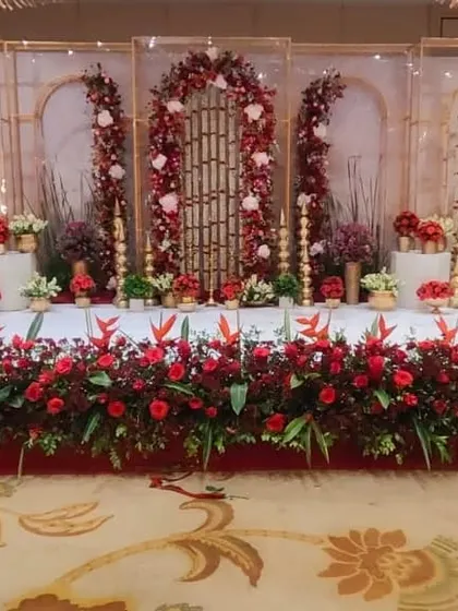 A full view of the red and white engagement stage, showing the line of floral arrangements at the front and the elegant backdrop.