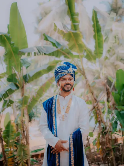 A handsome portrait of the groom in his traditional white and blue wedding attire.