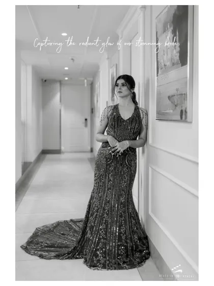 A stunning full-length portrait of the bride in her reception gown. The black and white treatment emphasizes the intricate details of her dress and her graceful posture.