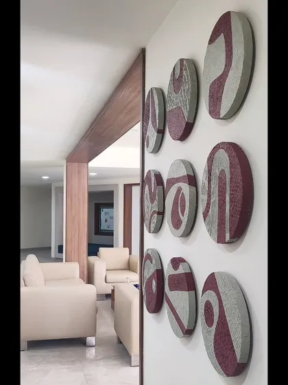 An angled view of the complete nine-piece circular art installation. This perspective highlights the three-dimensional quality of the panels and how they interact with the light in the room.