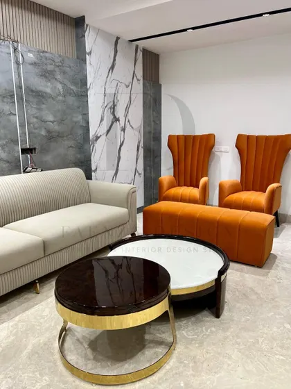 This living room setup showcases a variety of seating options, including a beige fluted sofa and two high-back chairs in a vibrant orange velvet. The nested coffee tables add a touch of modern geometry.