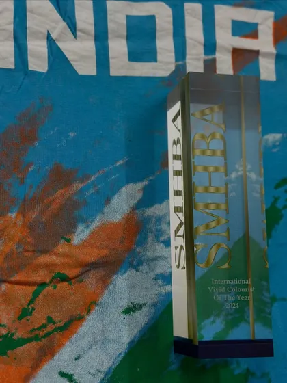 The trophy for the International Vivid Colorist of the Year 2024 from SMHBA, proudly displayed on an Indian flag-themed shirt. This win was not just for me, but for my country.