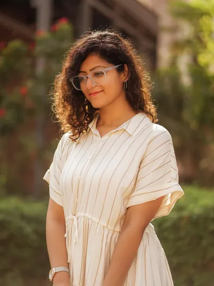 Capturing a candid, thoughtful moment. The soft, golden-hour light and natural green background create a warm and inviting portrait that feels completely authentic.