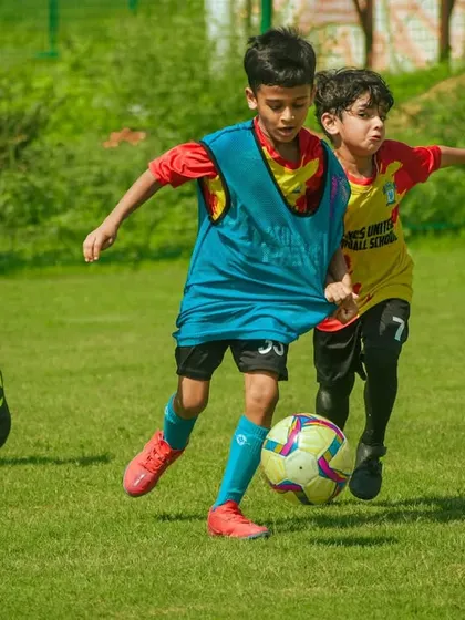 A young player in a bib dribbles through a crowd of opponents.