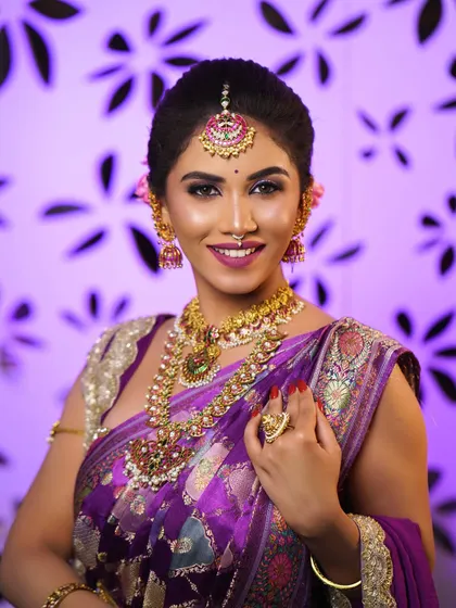 A classic bridal portrait with a focus on the flawless HD makeup and traditional jewellery. The purple saree provides a rich backdrop for the entire look.