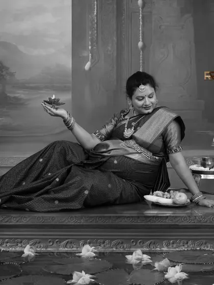 A timeless black and white portrait with a touch of divinity. The mom-to-be holds a diya (oil lamp), symbolizing light and hope, in this artistically rendered traditional scene.