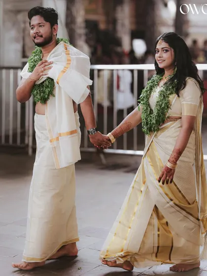 The quintessential Kerala wedding couple, walking hand-in-hand in their traditional mundu and kasavu saree after the temple ceremony.