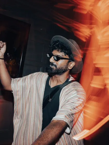 A partygoer feeling the music, sunglasses on, lost in the moment.