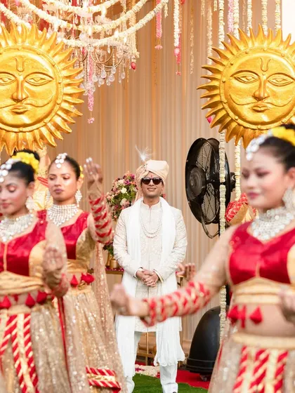 A close-up of the groom's royal entry, framed by his dancing entourage. The focus on the groom's confident stance amidst the motion and props emphasizes the personal yet grand nature of the celebration.
