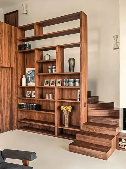 A unique storage solution where a large wooden bookshelf also functions as a staircase wall, seamlessly blending storage and architecture.