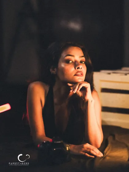 A confident and poised portrait. The camera prop adds a layer to her character, suggesting she is both the subject and the storyteller.