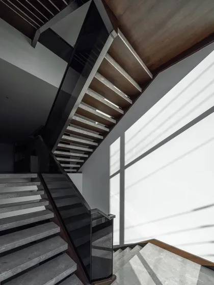 Light and shadow create a dramatic effect on the staircase of the Silhouette residence. The design uses simple materials like wood and glass to create a functional element that is also a beautiful study in form and geometry.
