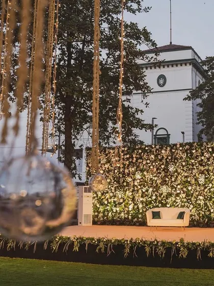 A simple yet sophisticated stage setup with a full floral wall and hanging disco balls. This design proves that even minimalist concepts can have a powerful impact, especially against a scenic backdrop.