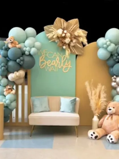 A unique take on the "We Can Bearly Wait" theme with a beautiful teal, beige, and silver color scheme. This setup includes a comfortable loveseat for guests, multiple teddy bears nestled in the balloons, and elegant pampas grass details.