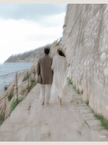 A soft, motion-blurred shot of the couple walking along a coastal path. This artistic technique evokes a sense of a shared journey and timeless romance.