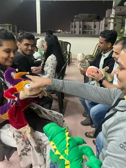 A group of adults exploring different types of puppets during a workshop. The goal is to help them understand how to make these characters come alive and use them to communicate effectively.