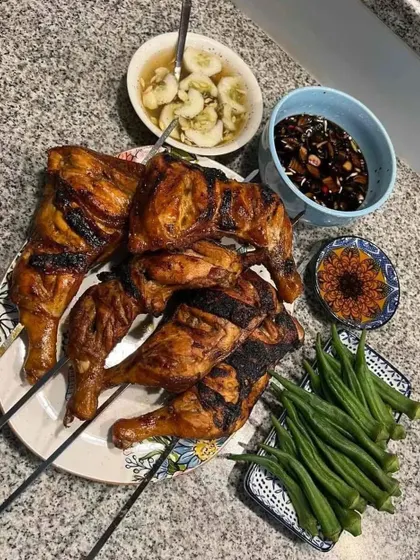A platter of delicious grilled chicken on skewers, served with okra and dipping sauces. A great option for a barbecue or outdoor event.