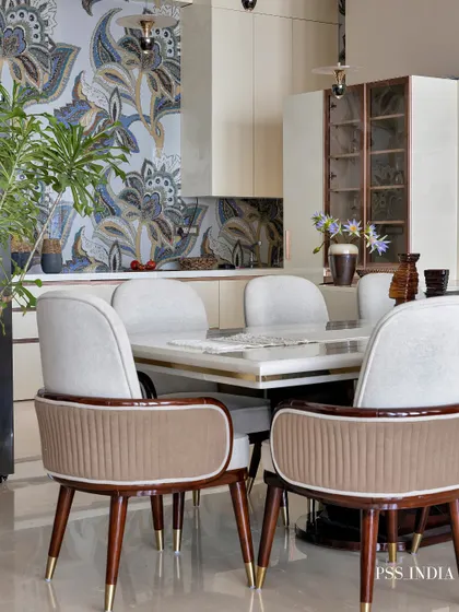 This dining room is all about creating an inviting atmosphere. The elegant white and brown chairs surround a marble-topped table, while a statement floral mosaic wall adds a touch of artistic flair.