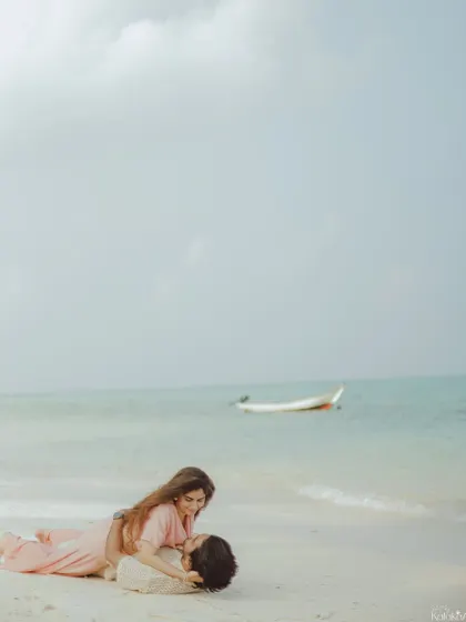 A playful and intimate moment on the sand, capturing genuine laughter and connection by the sea.