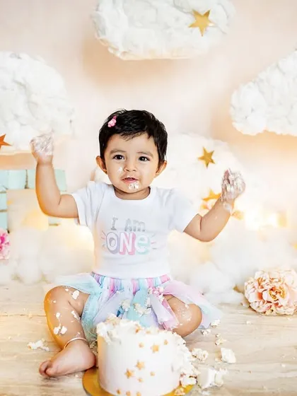 This little girl had a blast during her "I am one" cake smash, set against a dreamy cloud and star backdrop. It's pure joy and a little bit of mess, the perfect recipe for a first birthday photoshoot.
