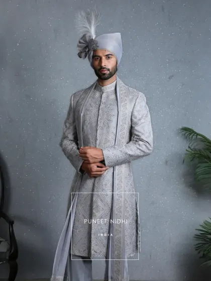 Inspired by Mughal grandeur, this powder blue sherwani is a vision of heritage. It is embroidered with intricate zari, handwoven florals, and sequins that sparkle like blessings, making it a living legacy carried forward with pride.