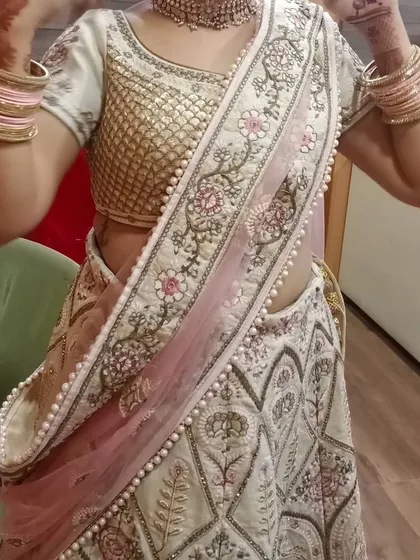 A client trying on the ivory lehenga, showing how the dupatta can be draped. The pearl border on the dupatta adds a touch of elegance to the overall look.