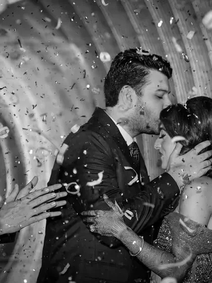 A beautiful moment as the groom kisses his bride's forehead amidst a shower of confetti during their Sangeet celebration in the UAE.