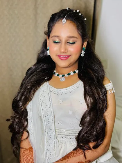 A close-up of the teenage client's makeup, featuring a pop of green liner and glossy lips.