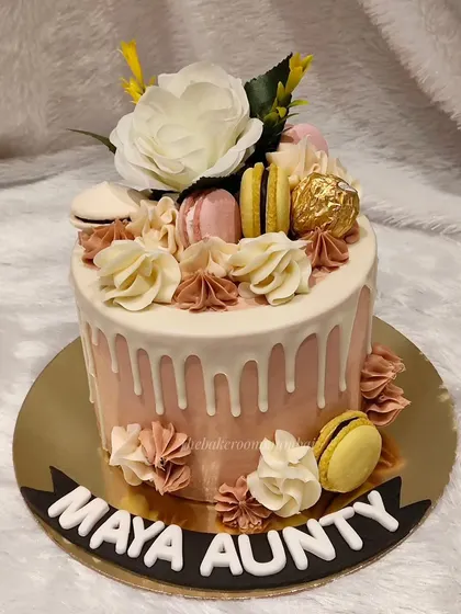 A beautiful drip cake adorned with fresh flowers, macarons, and a Ferrero Rocher. The combination of textures and flavors makes this a delightful and aesthetically pleasing cake.