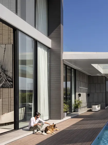 A moment of quiet connection in the Ananda backyard. The expansive wooden deck provides ample space for relaxation by the pool, with the home's modern architecture serving as a stunning backdrop.